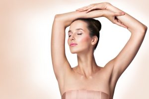 Beautiful woman lifts her thin, sleek arms above her head, unworried about her sleeveless outfit