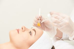 Woman lies down with her hair out of her face while she undergoes a guided chemical peel
