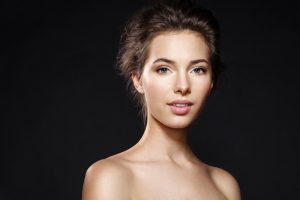 Gorgeous one woman shows off her beautiful lips and teeth while standing in front of a black background.