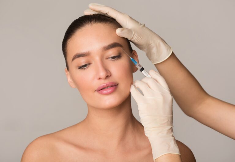 Beautiful woman with full eyebrows tilts her head and smiles during facial injections to add volume to her temples