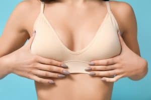 Woman holds her small breasts before a fat transfer breast augmentation procedure