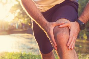 Jogging man holds his knee after an injury
