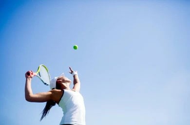 Woman serves during a tennis match after correcting her elbow injury.