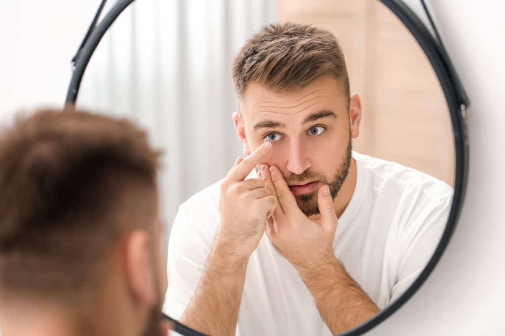 Young,Man,Putting,In,Contact,Lenses,Near,Mirror