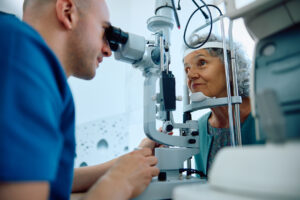 Ophthalmologist examining an older woman’s cornea with a slit-lamp microscope before discussing DSEK or full-thickness corneal transplant options.